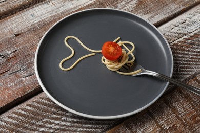 Photo of Heart made of tasty spaghetti, fork and tomato on wooden table
