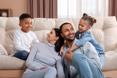 Photo of Happy international family with children near sofa at home