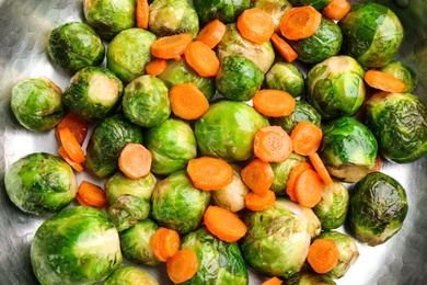 Photo of Roasted Brussels sprouts with carrot in frying pan, closeup