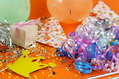 Photo of Colorful serpentine streamers and other party accessories on orange background