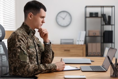 Military service. Young soldier working at wooden table in office