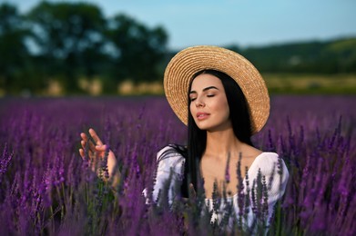 Beautiful young woman with straw hat in lavender field