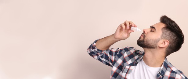 Photo of Man using nasal spray on beige background