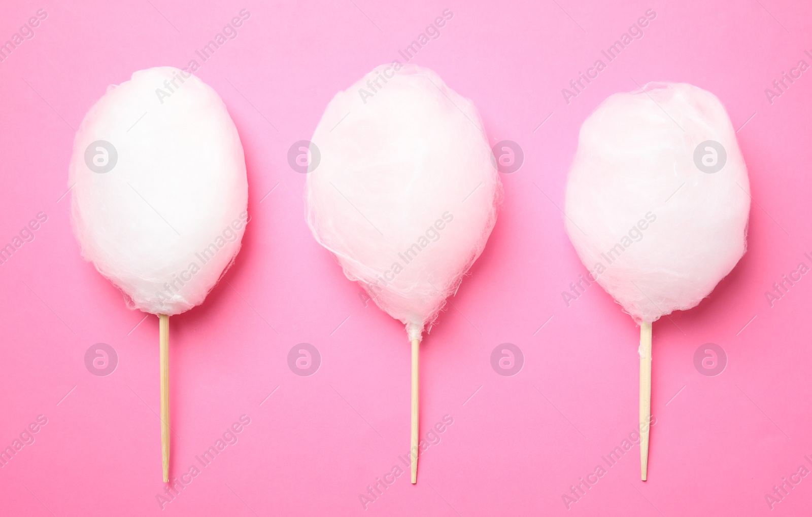 Photo of Sticks with yummy cotton candy on color background, top view