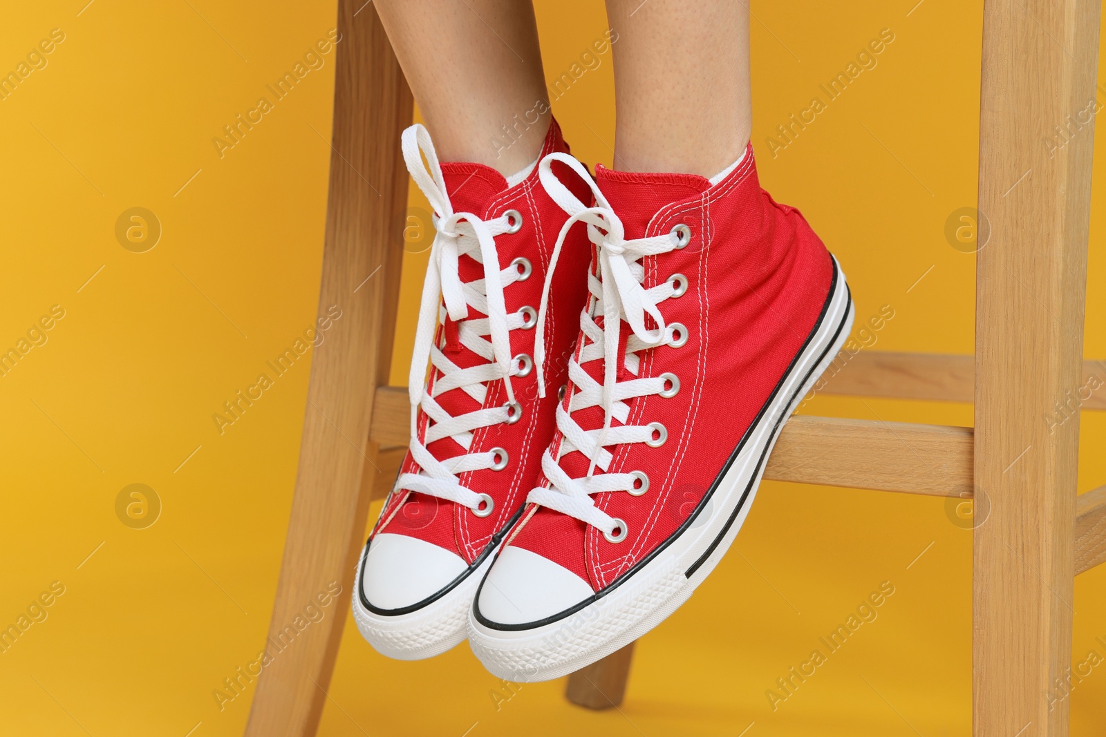 Photo of Woman in stylish gumshoes on yellow background, closeup