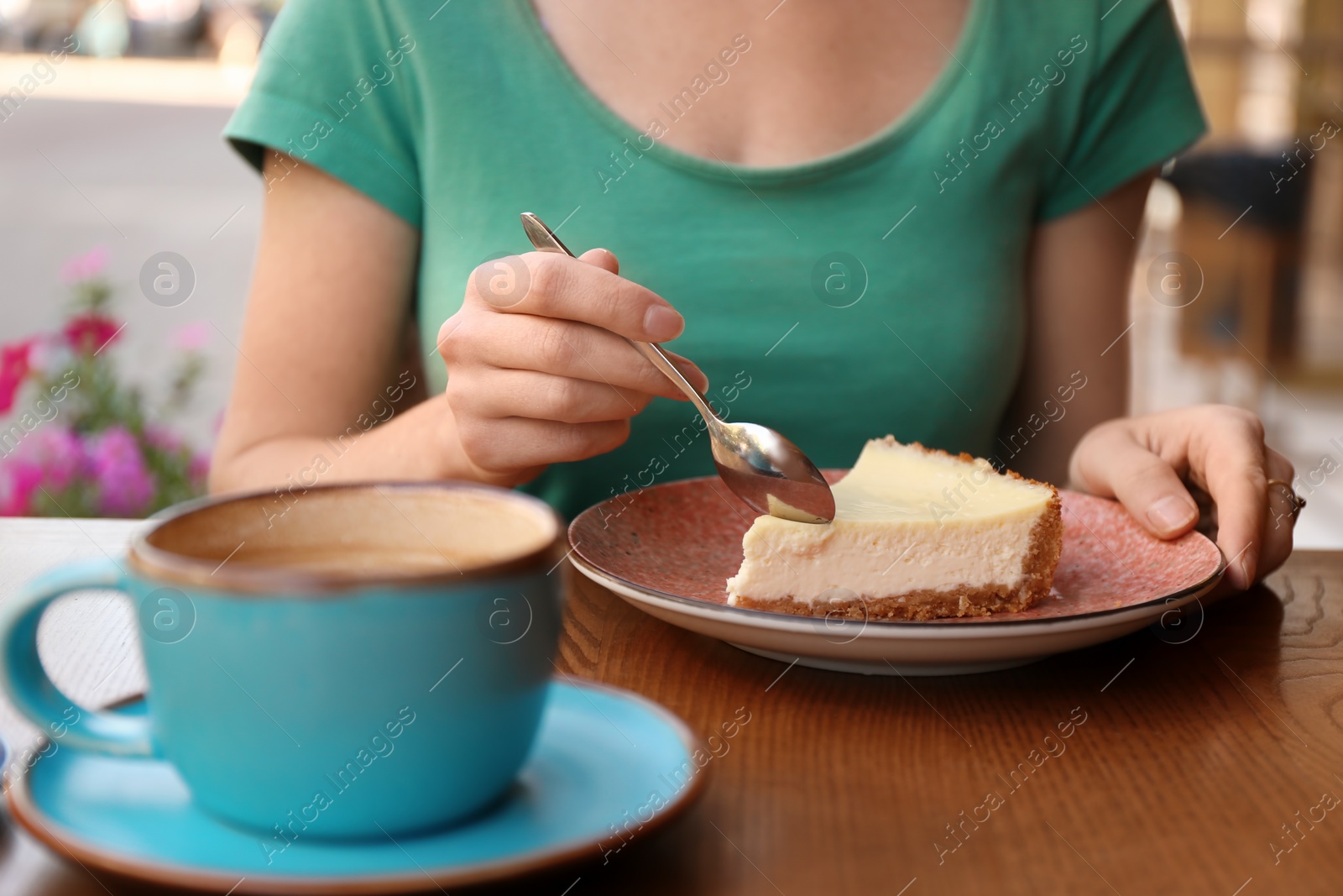 Photo of Woman eating slice of cheesecake at table, closeup