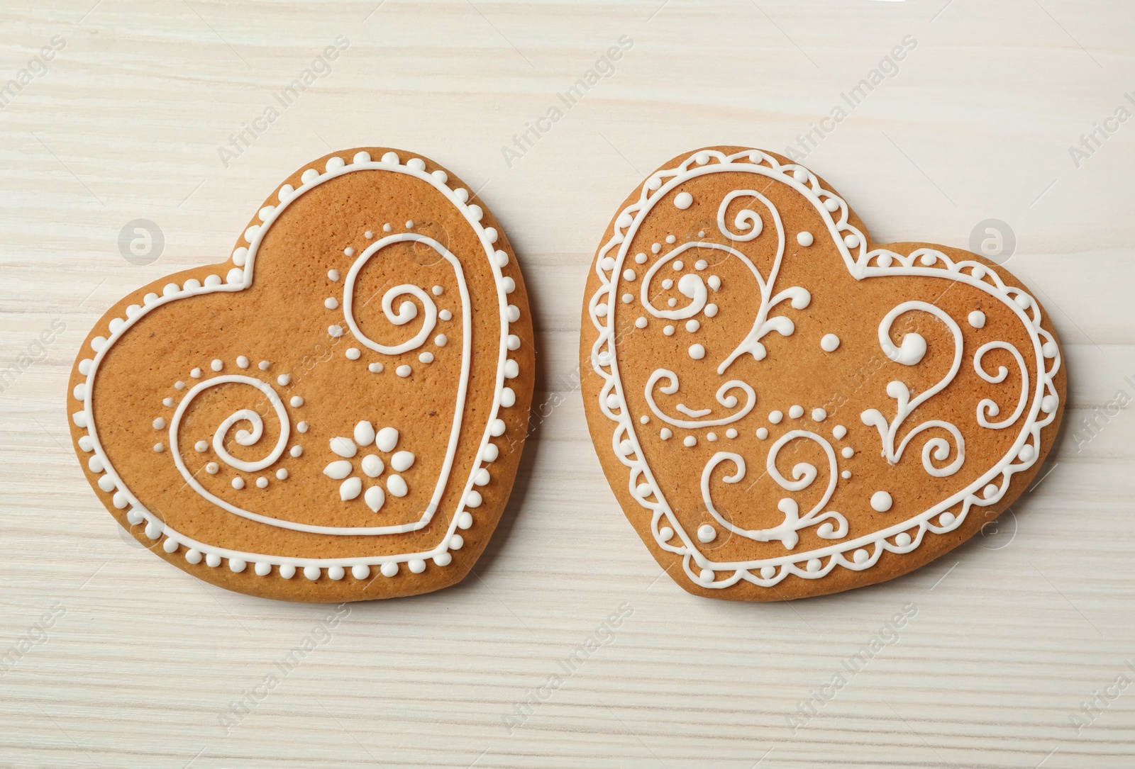 Photo of Tasty heart shaped gingerbread cookies on white wooden table, flat lay