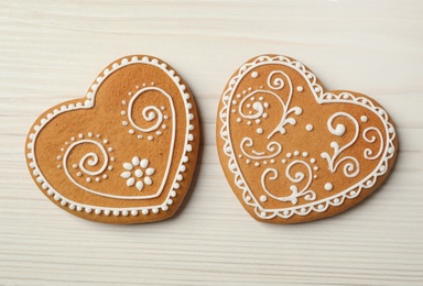 Tasty heart shaped gingerbread cookies on white wooden table, flat lay