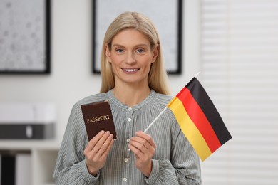 Photo of Immigration. Happy woman with passport and flag of Germany indoors