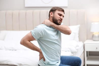 Photo of Man suffering from back pain at home. Bad posture problem