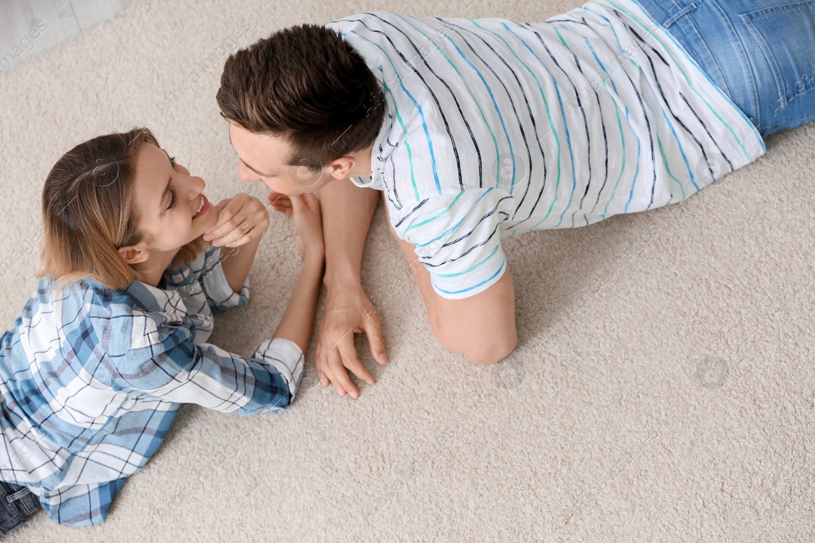 Photo of Lovely young couple lying on cozy carpet at home