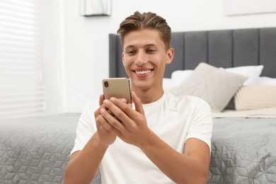 Photo of Happy young man having video chat via smartphone indoors