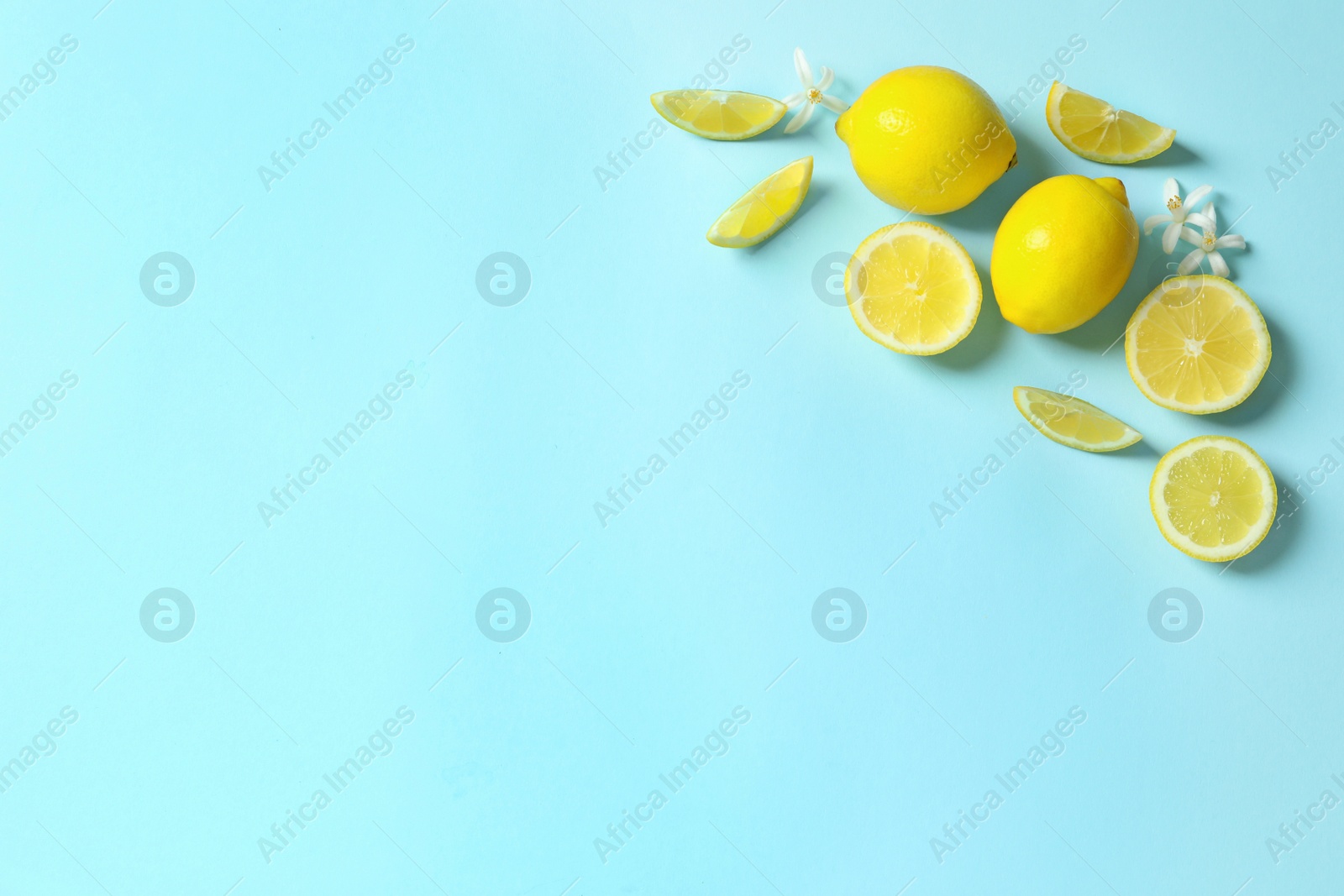 Photo of Frame made of lemons and flowers on color background, flat lay with space for text. Citrus fruits