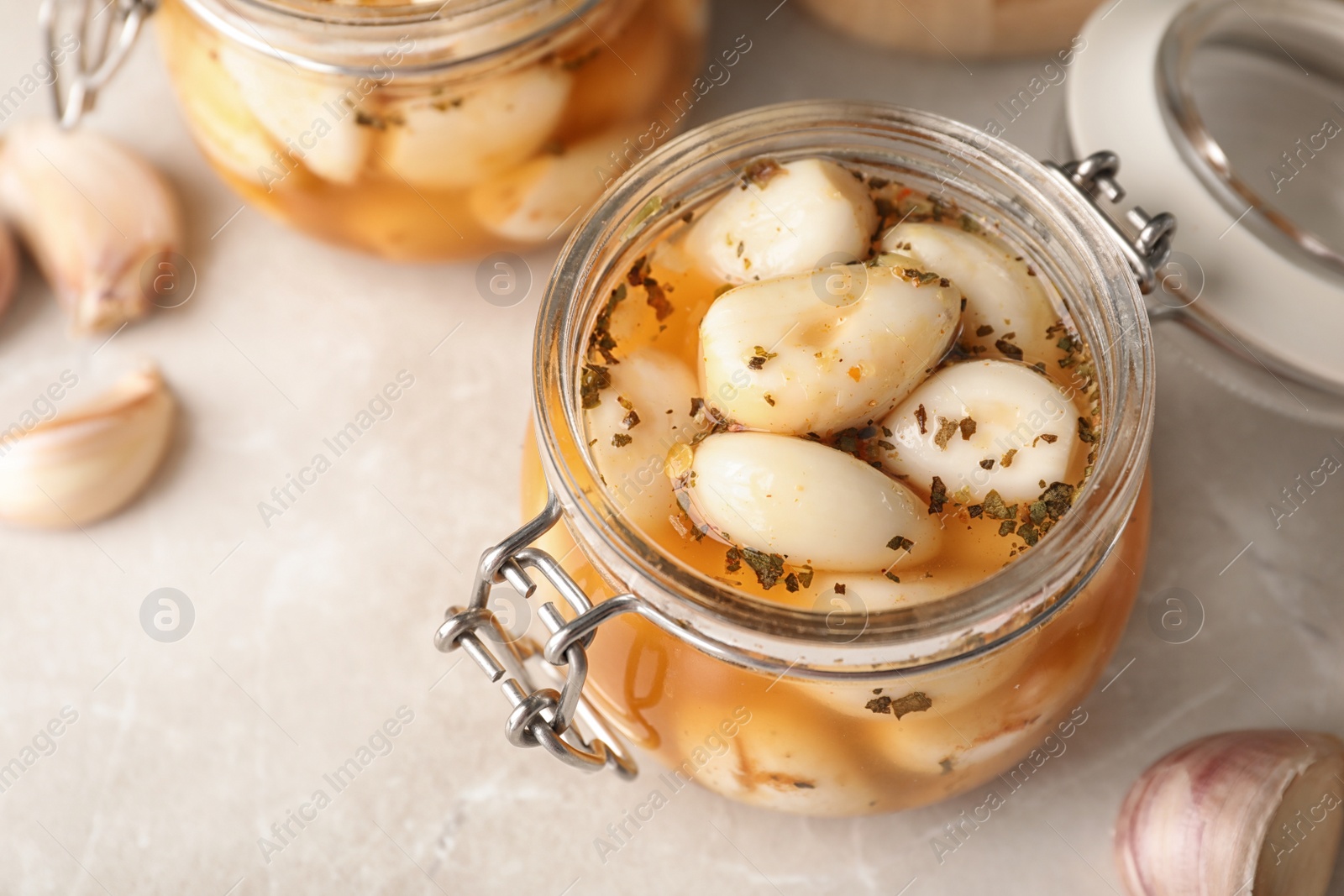 Photo of Preserved garlic in glass jar on table, closeup. Space for text