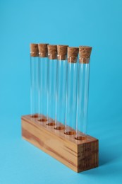 Test tubes in wooden stand on light blue background. Laboratory glassware