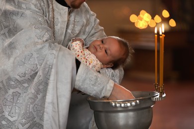 MYKOLAIV, UKRAINE - FEBRUARY 27, 2021: Priest holding baby in Kasperovskaya icon of Mother of God cathedral during baptism ceremony, closeup