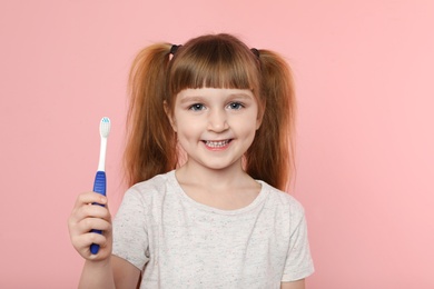 Little girl with toothbrush on color background. Teeth care