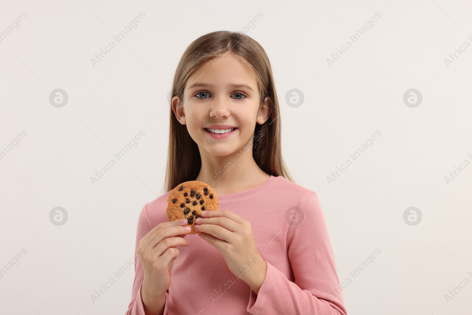 Photo of Cute girl with chocolate chip cookie on white background