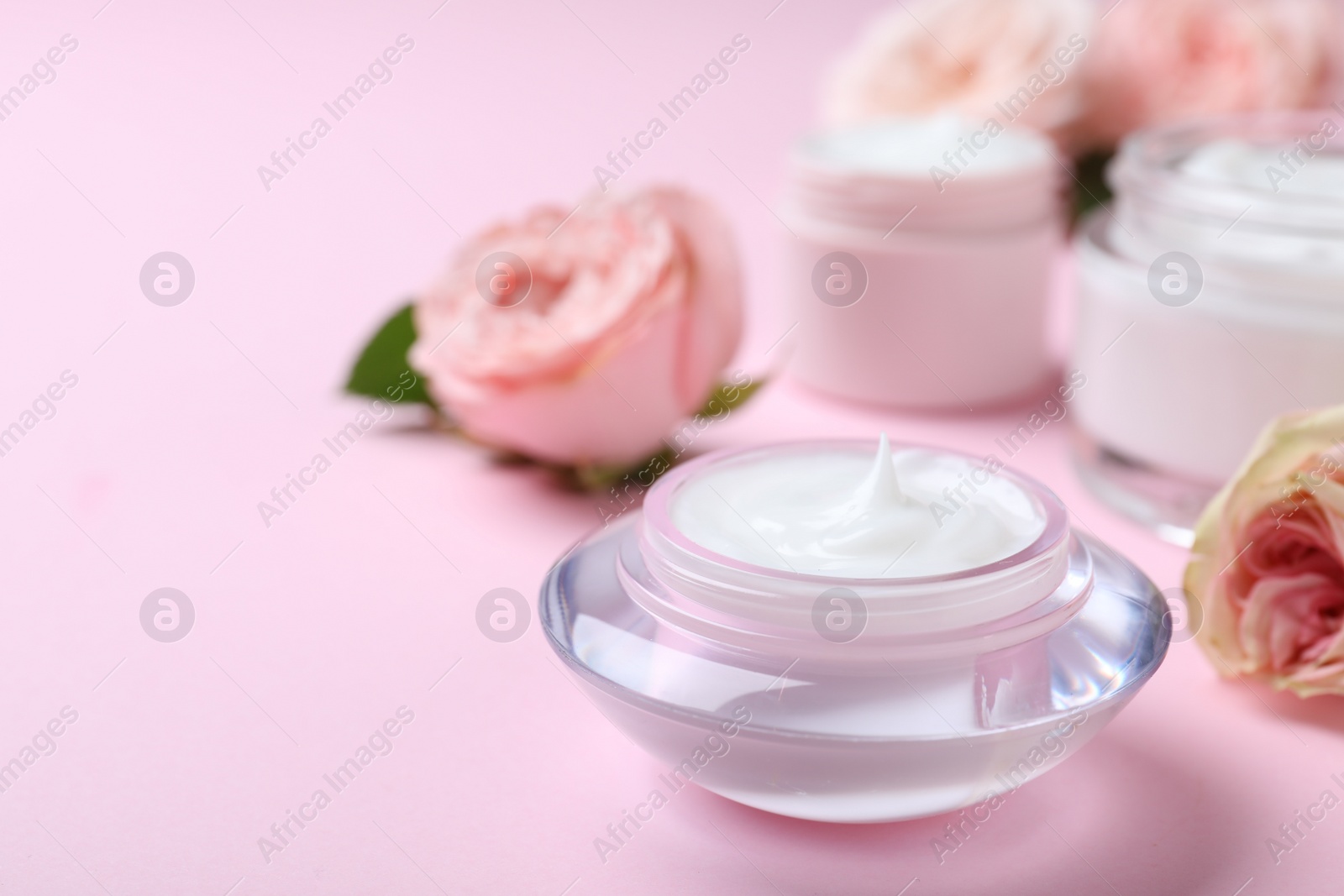 Photo of Jar of organic cream and flower on pink background. Space for text