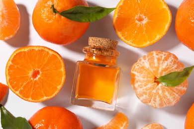 Aromatic tangerine essential oil in bottle, leaves and citrus fruits on white table, flat lay