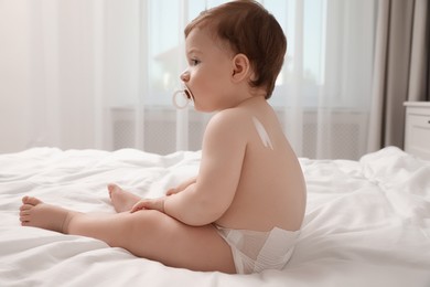 Cute little baby with cream on skin indoors