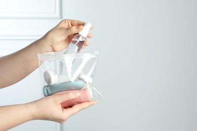 Photo of Woman packing cosmetic travel kit indoors, closeup. Space for text