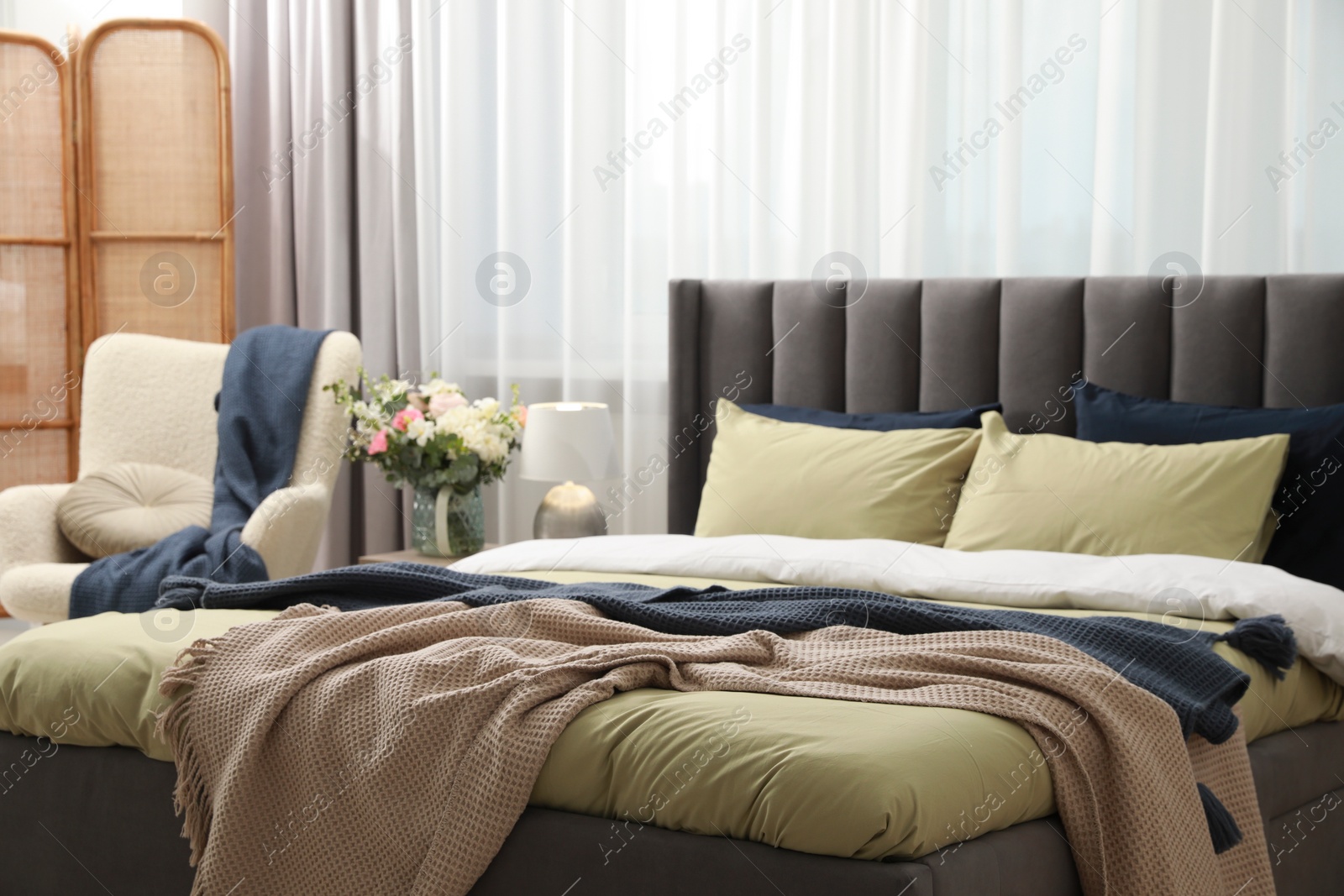 Photo of Comfortable bed with cushions and bedding in room. Stylish interior