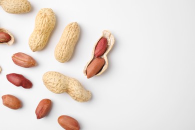 Fresh peanuts on white table, flat lay. Space for text