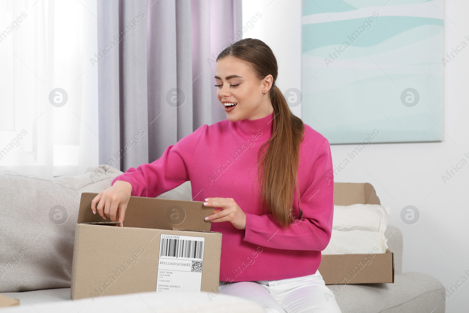 Photo of Emotional woman unpacking parcel at home. Online store