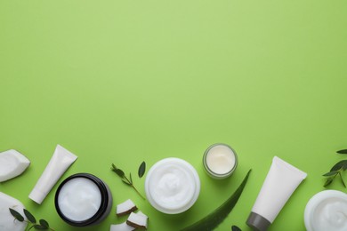 Photo of Body cream and other cosmetic products with ingredients on light green background, flat lay. space for text