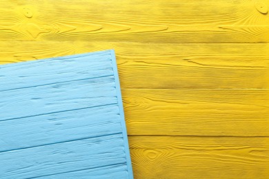 Photo of Light blue and yellow wooden surfaces as background, top view