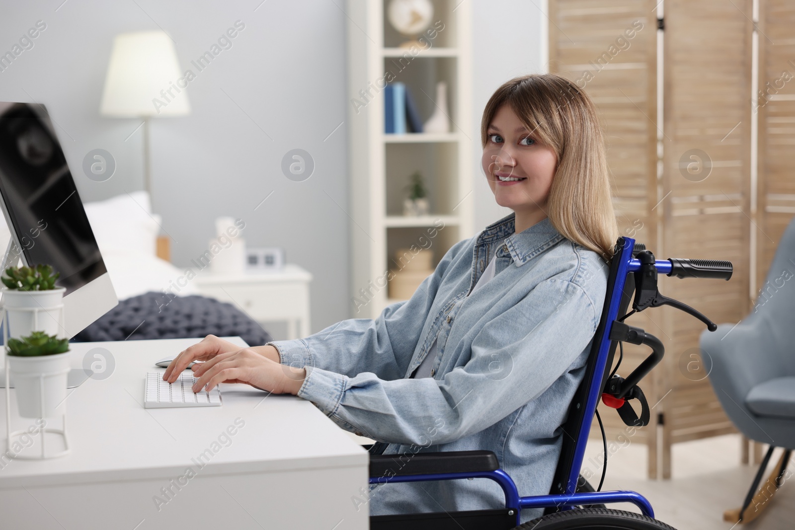 Photo of Woman in wheelchair using computer at table in home office