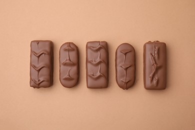 Different tasty chocolate bars on beige background, flat lay