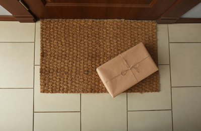 Photo of Parcel on rug near door, flat lay. Delivery service