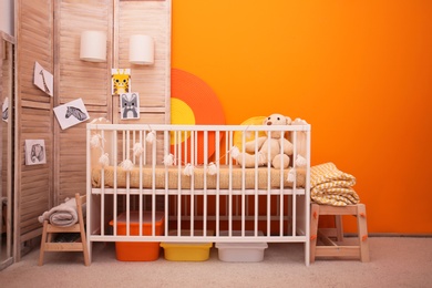 Photo of Baby room interior with crib near color wall