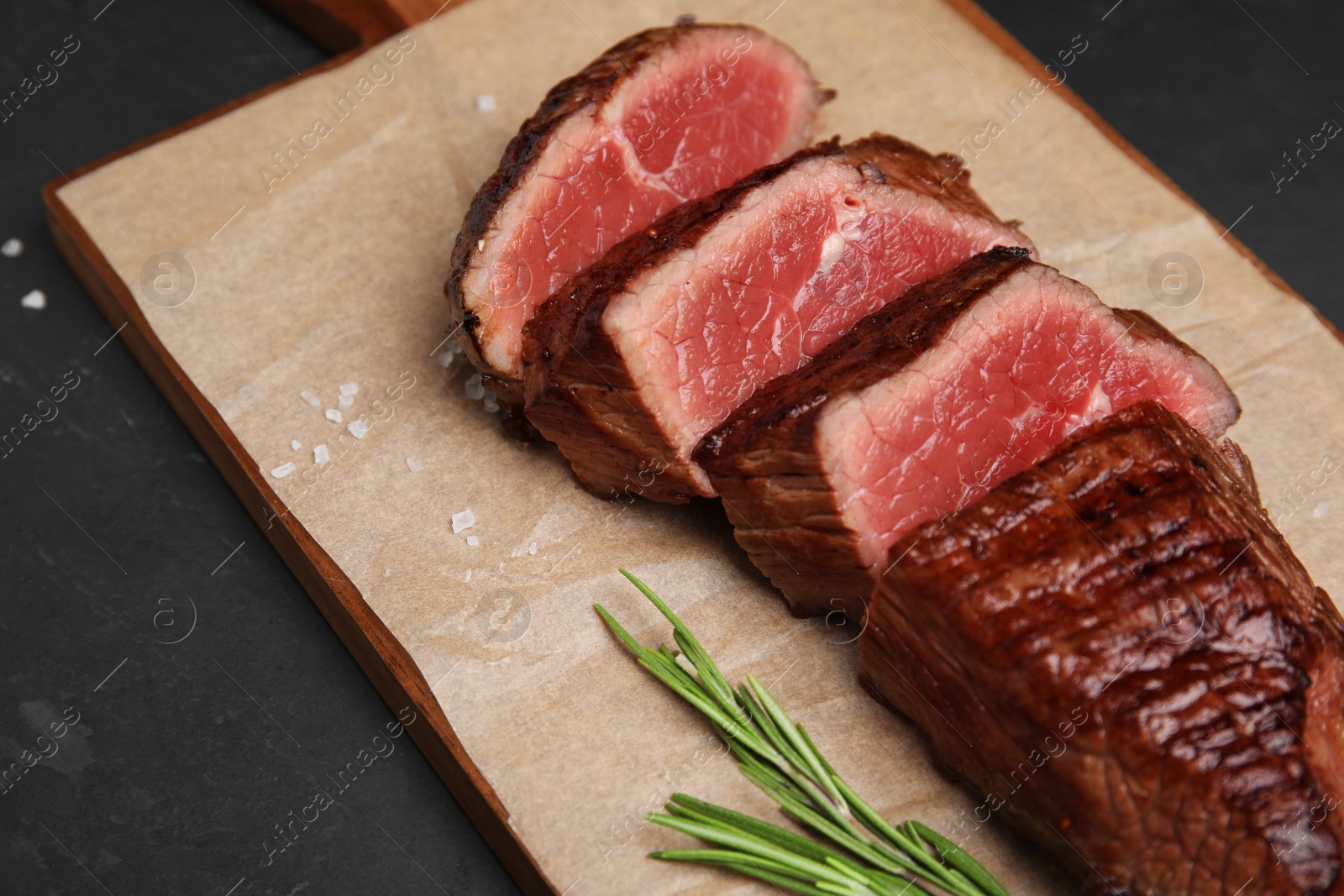 Photo of Delicious sliced beef tenderloin on black table, closeup