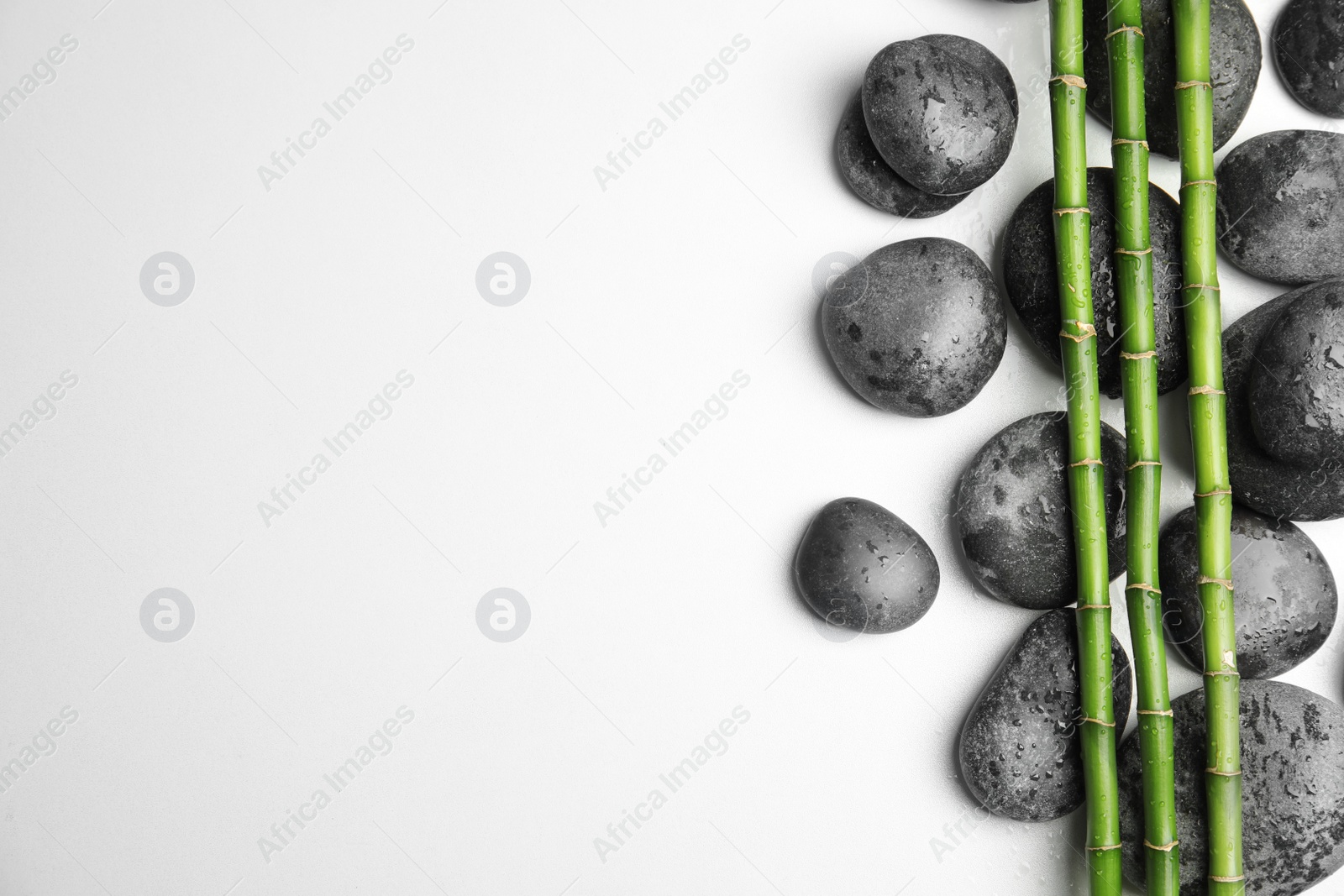 Photo of Wet zen stones and bamboo on white background, top view with space for text