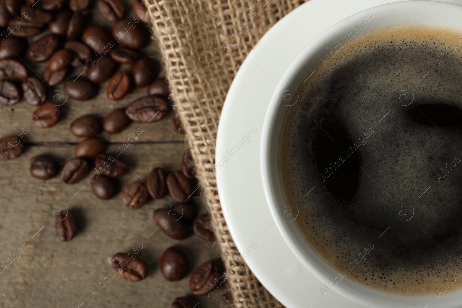 Photo of Cup of aromatic coffee on wooden table, top view. Space for text