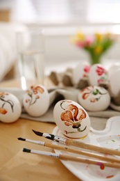 Photo of Beautifully painted Easter eggs and brushes on wooden table