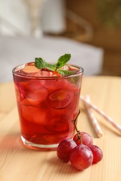 Photo of Soda water with grapes, ice and mint on wooden table indoors. Refreshing drink