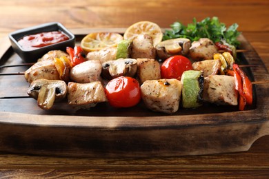 Delicious shish kebabs with grilled vegetables served on wooden table, closeup