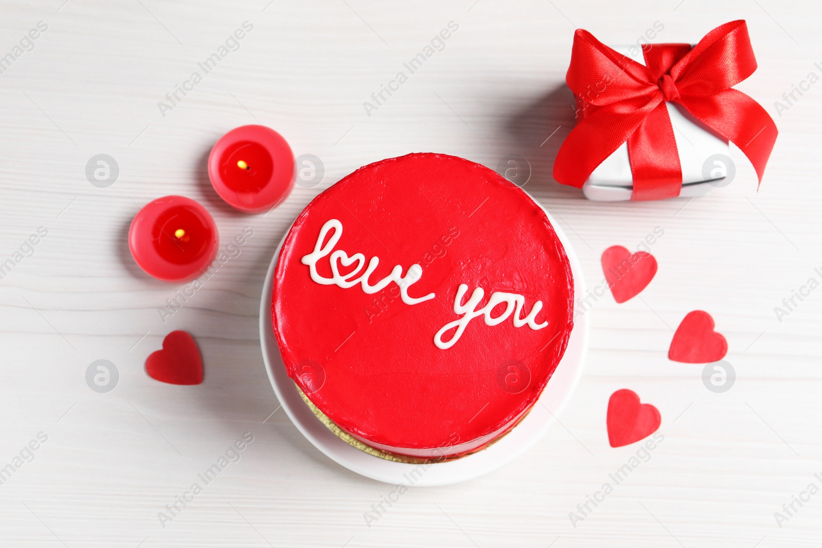 Photo of Bento cake with text Love You, gift box, candles and paper hearts on white wooden table, flat lay. St. Valentine's day surprise