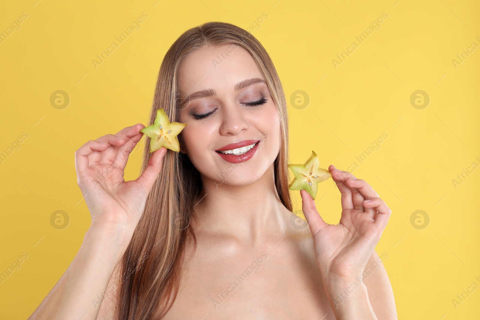 Photo of Young woman with cut carambola on yellow background. Vitamin rich food