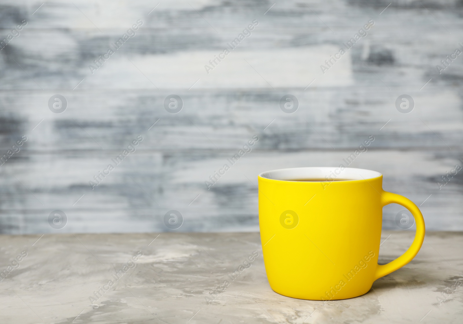 Photo of Yellow ceramic cup with hot aromatic coffee on table