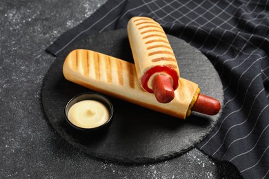 Tasty french hot dogs and dip sauce on black table