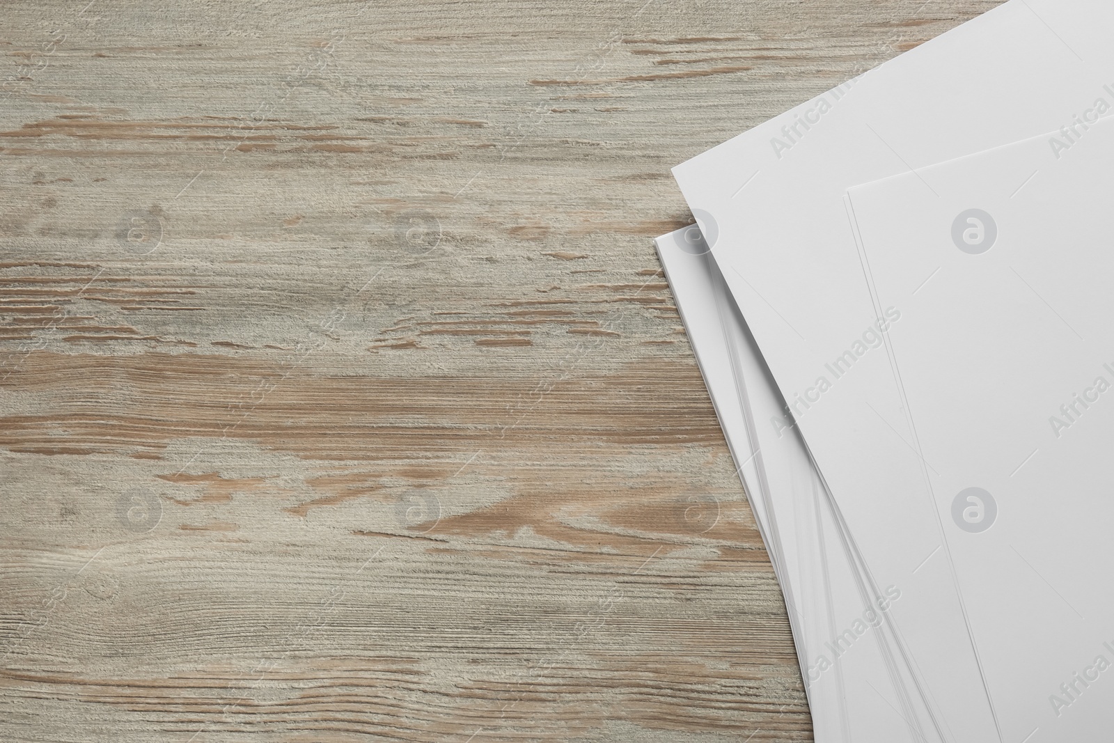 Photo of White paper sheets on wooden table, top view. Space for text