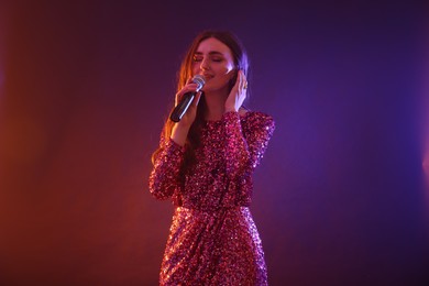 Photo of Emotional woman with microphone singing on bright background