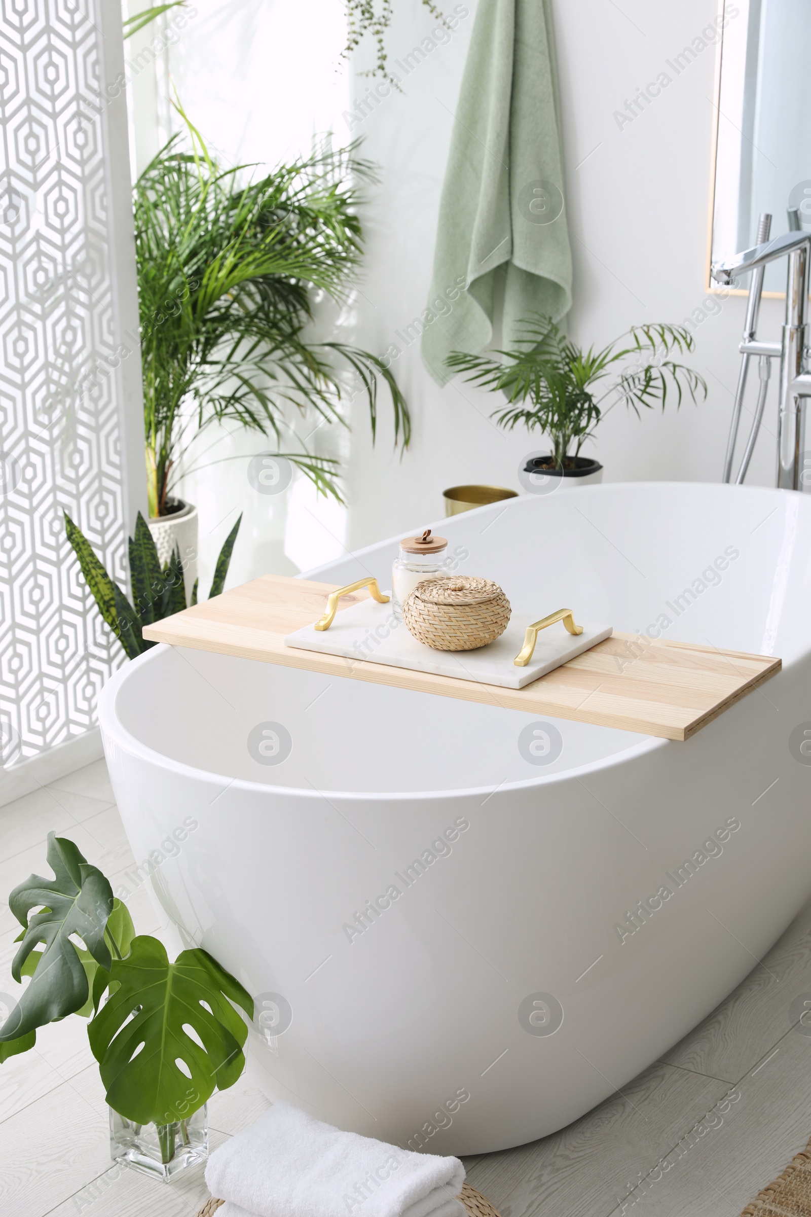 Photo of Stylish bathroom interior with modern tub, houseplants and beautiful decor. Home design