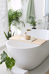 Photo of Stylish bathroom interior with modern tub, houseplants and beautiful decor. Home design