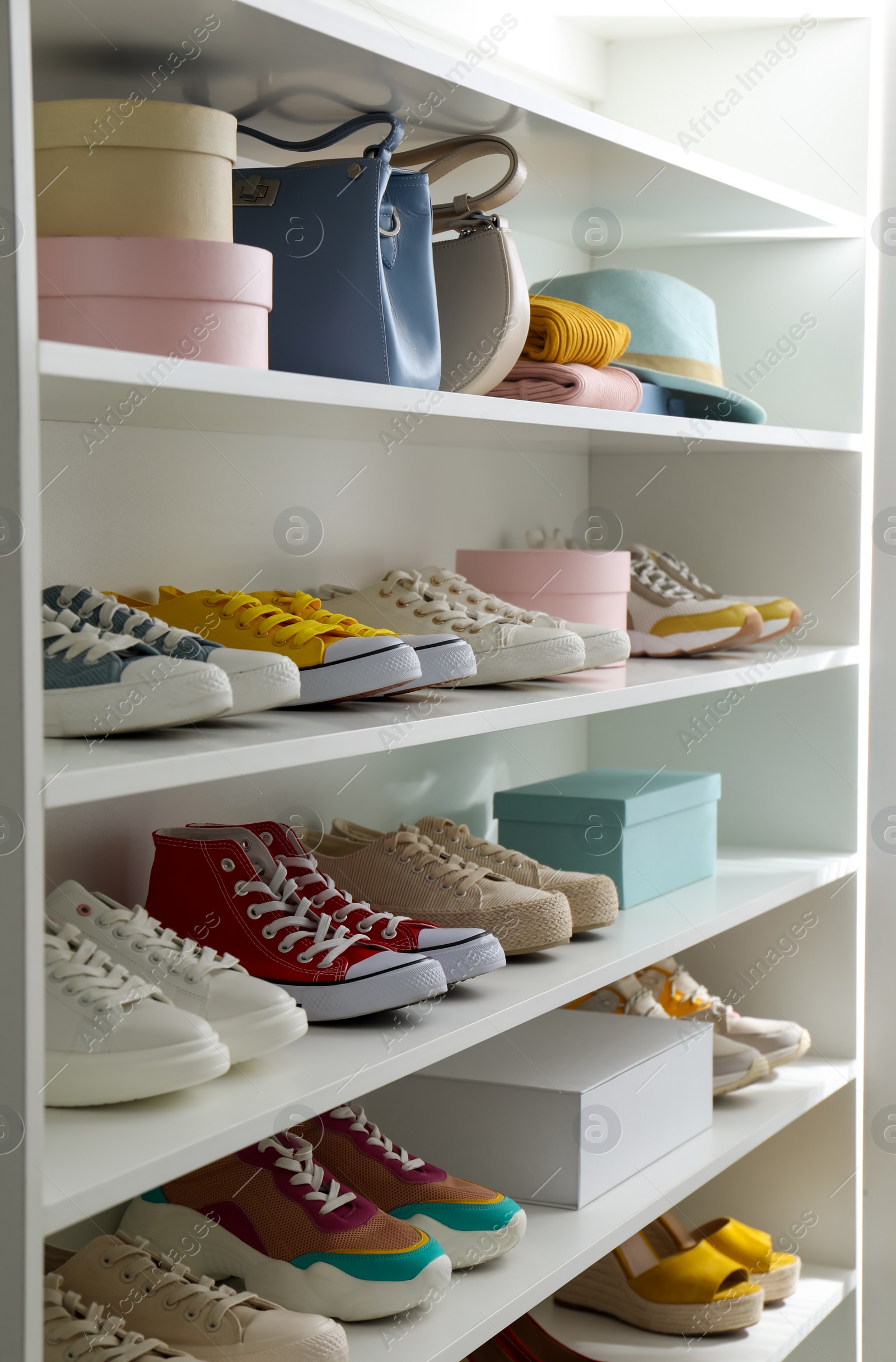 Photo of White shelving unit with collection of colorful sneakers and accessories